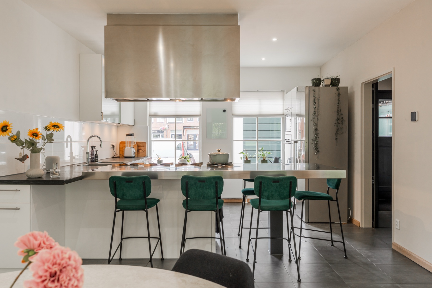 Open keuken met rvs-bar en groene barkrukken